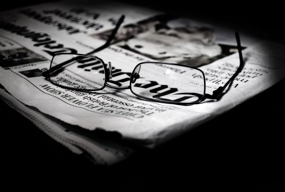 Giornalismo. Giornali impilati e occhiali: diritti e doveri di chi legge e di chi scrive